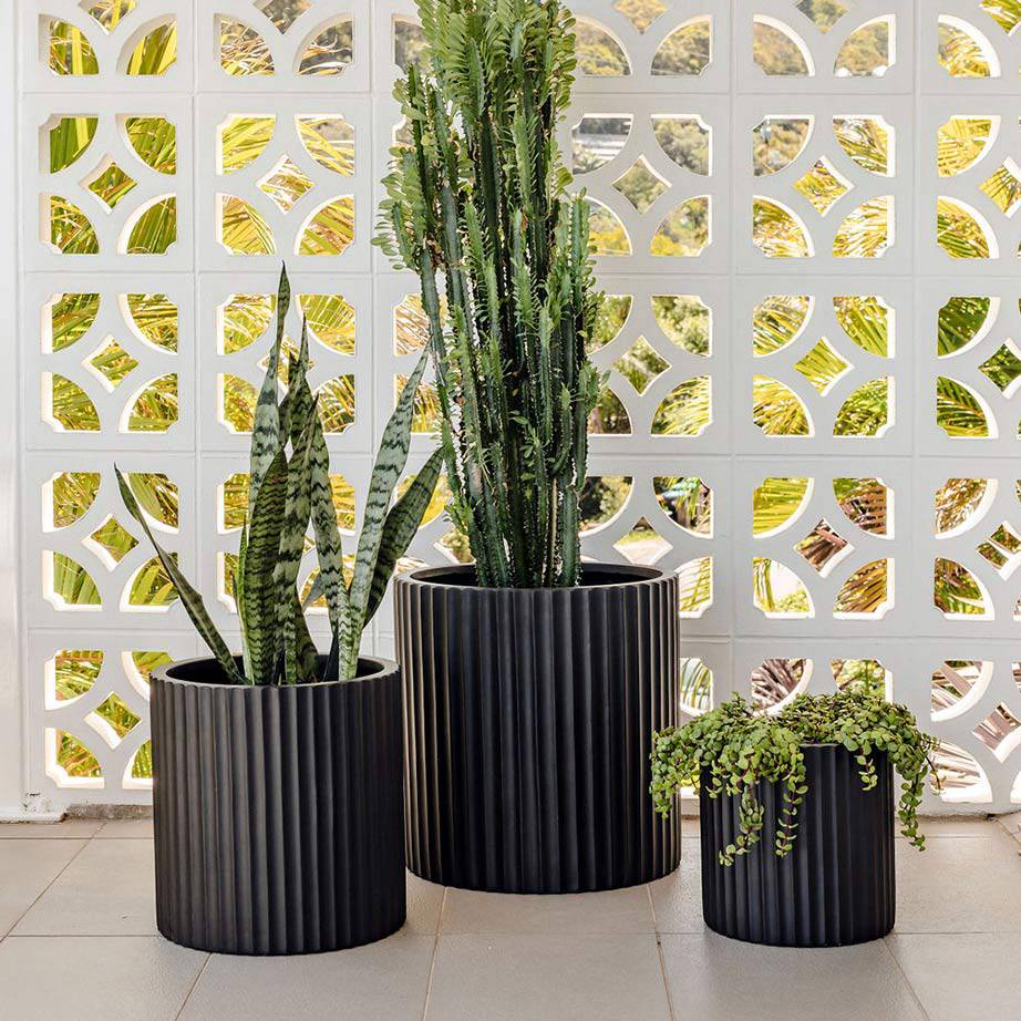 Black outdoor garden pots on a soft grey tiled patio.